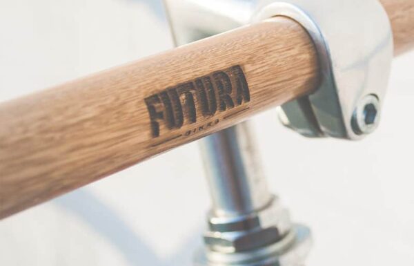 Close-up of wooden bicycle handlebar with Futura Bikes logo.